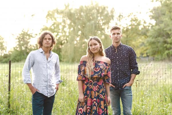 three siblings stand together in a field