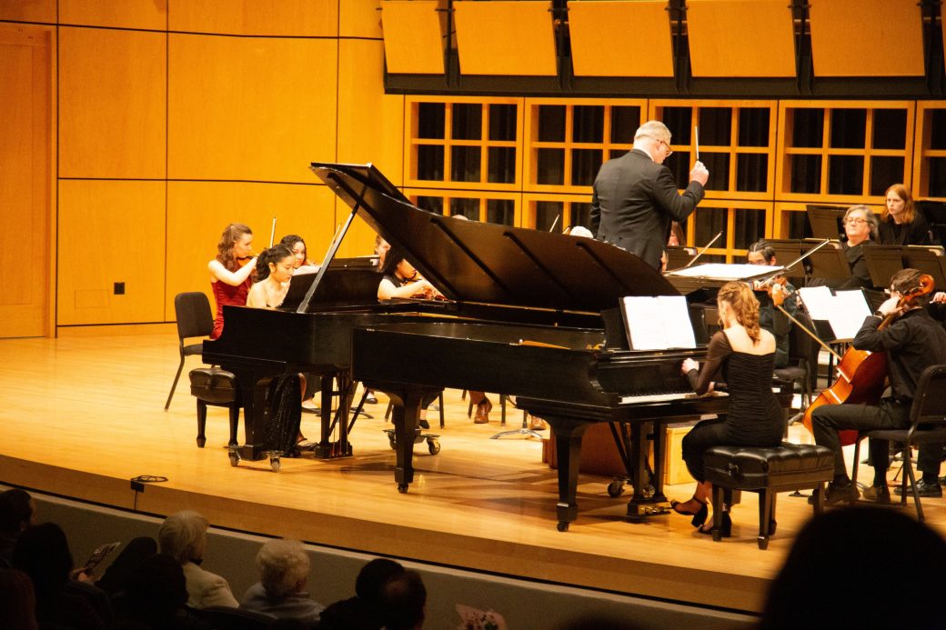 Two women playing piano in a stage