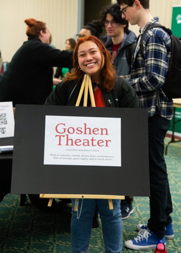 Women carrying a board of Goshen theater at Community Engagement Fair 2024