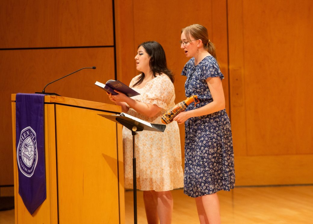 Two women on the stage on of them is doing a speech