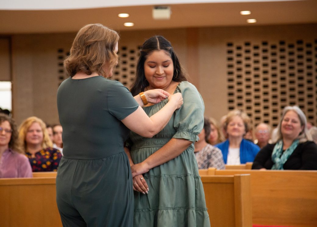 Woman putting a pin in a other woman at Commencement 2024: Nurses' Pinning Ceremony
