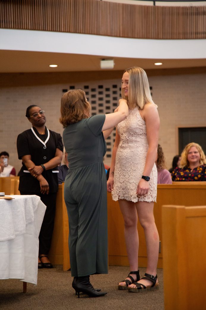 Woman putting a pin at Commencement 2024: Nurses' Pinning Ceremony