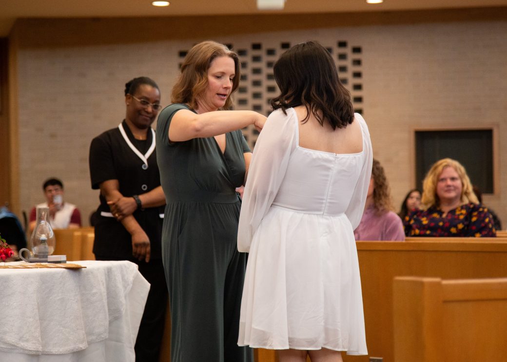 Woman putting a pin in other woman at Commencement 2024: Nurses' Pinning Ceremony