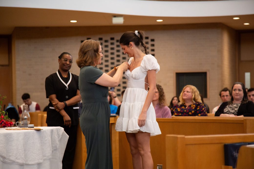 Woman putting a pin in other woman at Commencement 2024: Nurses' Pinning Ceremony