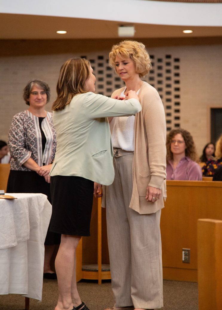 Woman putting a pin in a other woman at Commencement 2024: Nurses' Pinning Ceremony