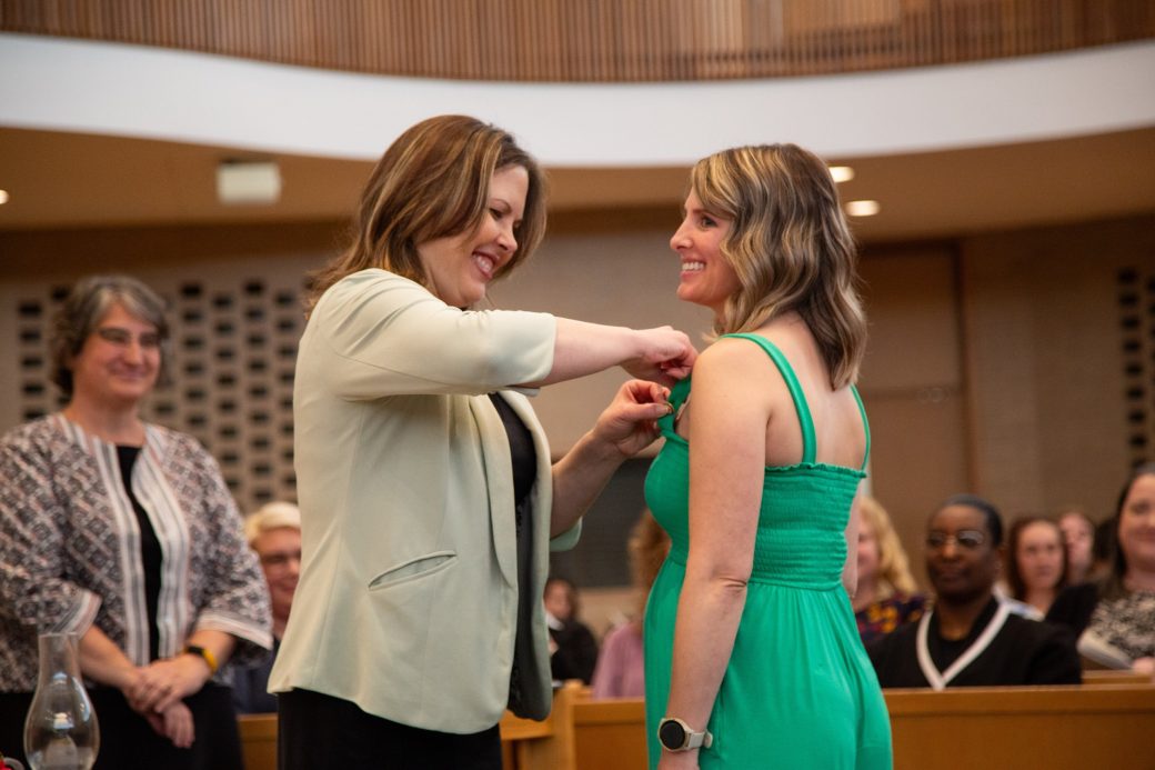 Woman putting a pin in other woman at Commencement 2024: Nurses' Pinning Ceremony