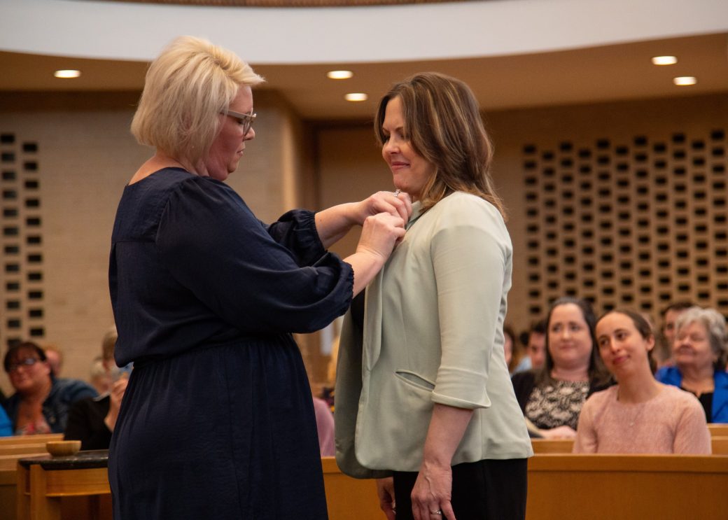Woman putting a pin in another woman at Commencement 2024: Nurses' Pinning Ceremony