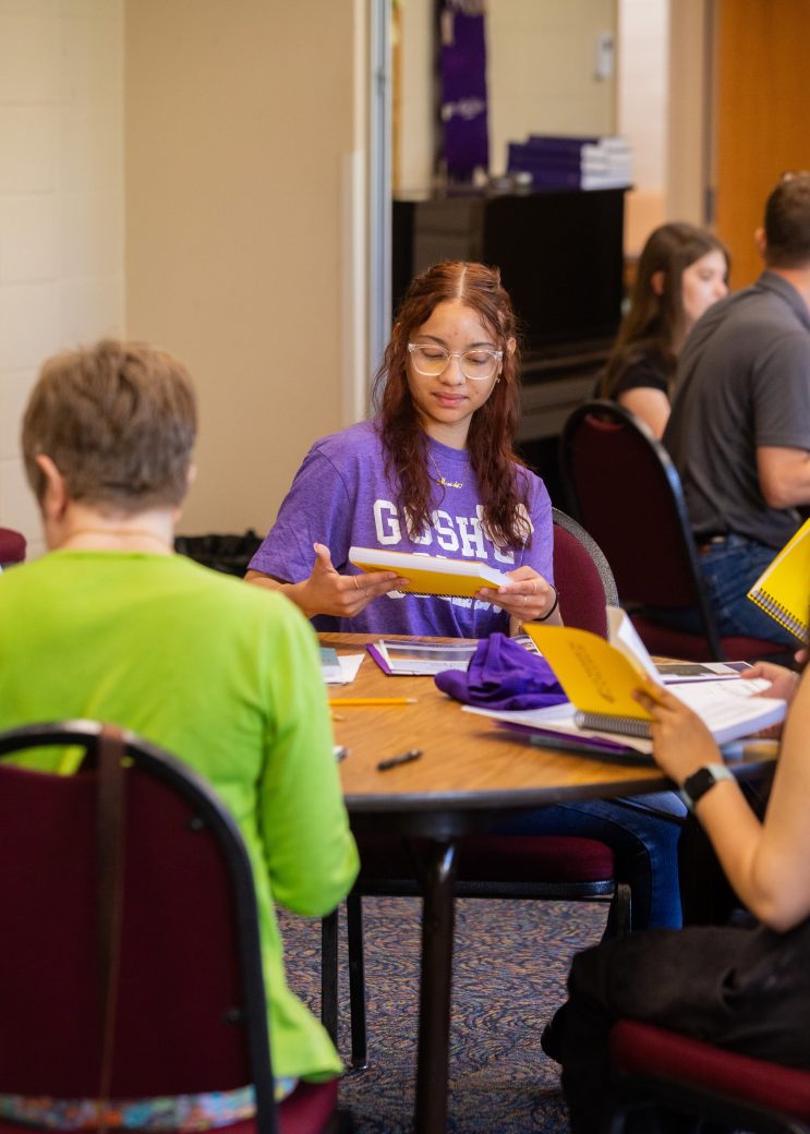 Goshen college students talking doing writing in a notebok