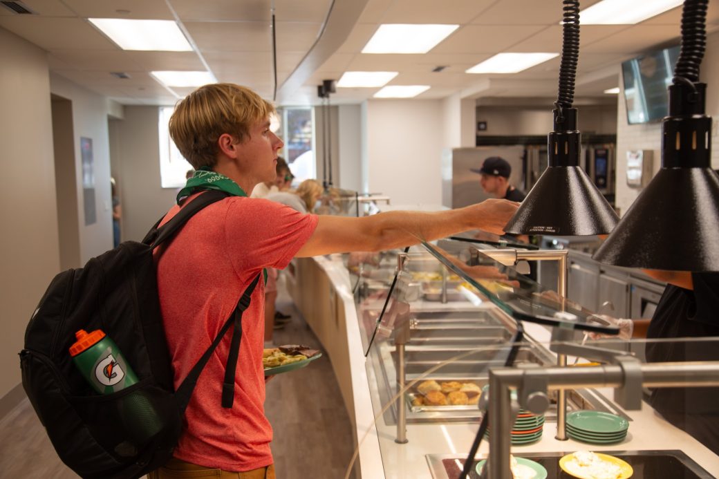 Student ordering food from the grill in the dining hall.
