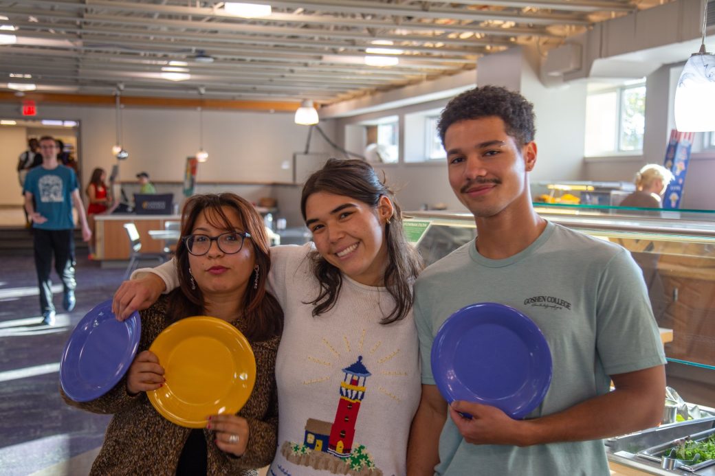 Three Goshen college students smiling to the camera at Westlawn Dining Hall