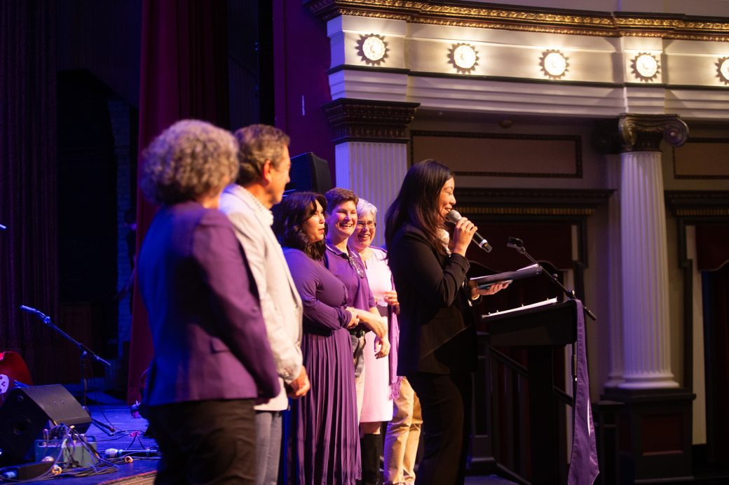 People at Connectpalooza's stage and a woman giving a speech at the podium