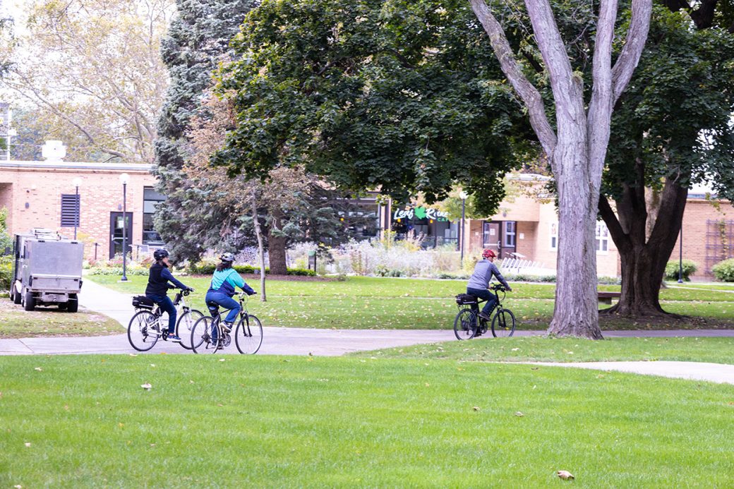 Three people riding bike at Homecoming Weekend 2024