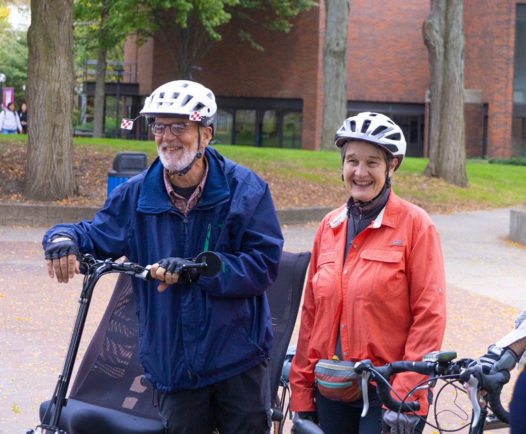 A man and a woman with bikes smiling to the camera at Homecoming Weekend 2024