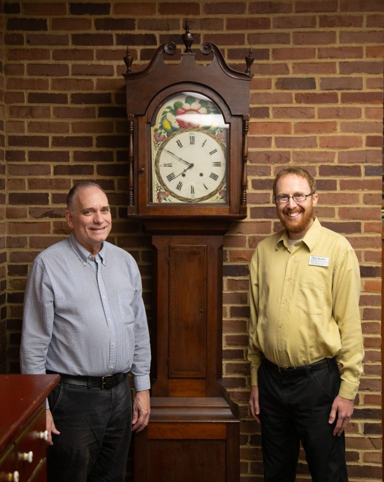 Two men standing infront of an old clock