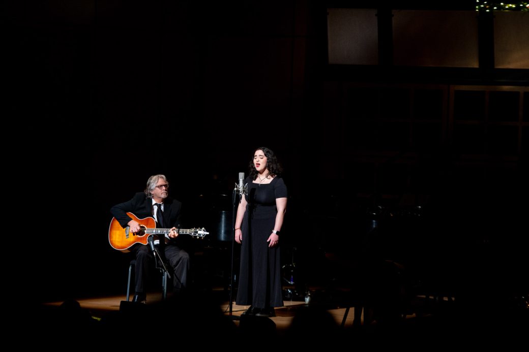 Woman singing and a man playing an acoustic guitar