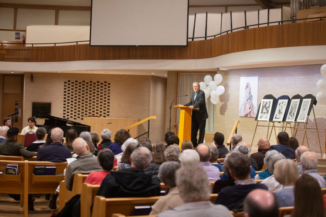 Public in the chapel paying attention at the man doing a speech at stage's pulpit