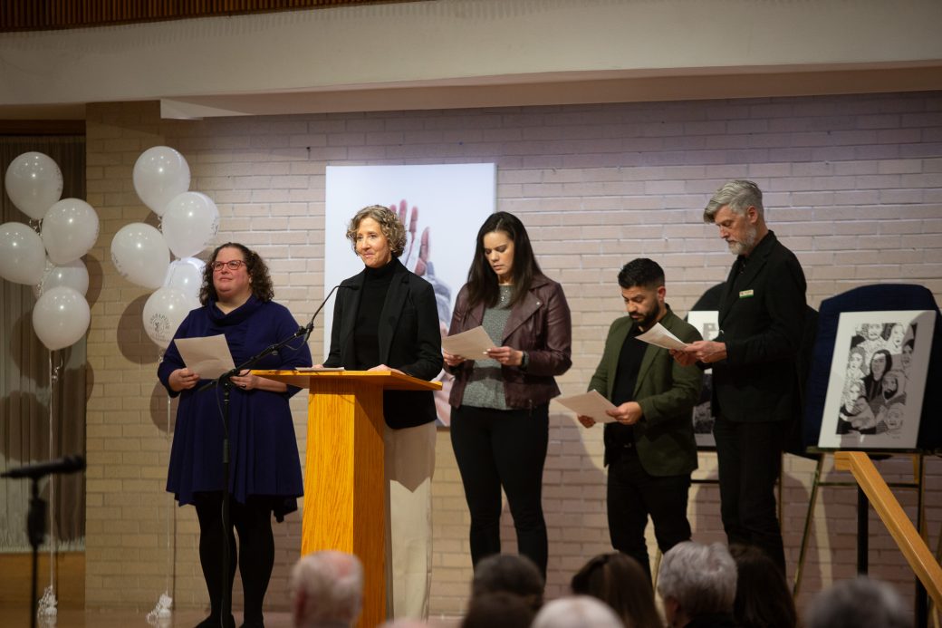 woman doing a speech at stage's pulpit and other people at the stage reading their papers