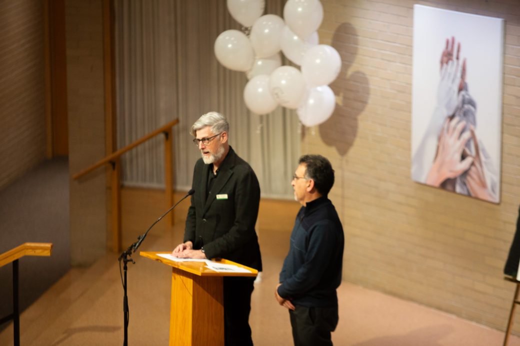 Man giving a speech at the stage's pulpit at Anabaptism Celebration