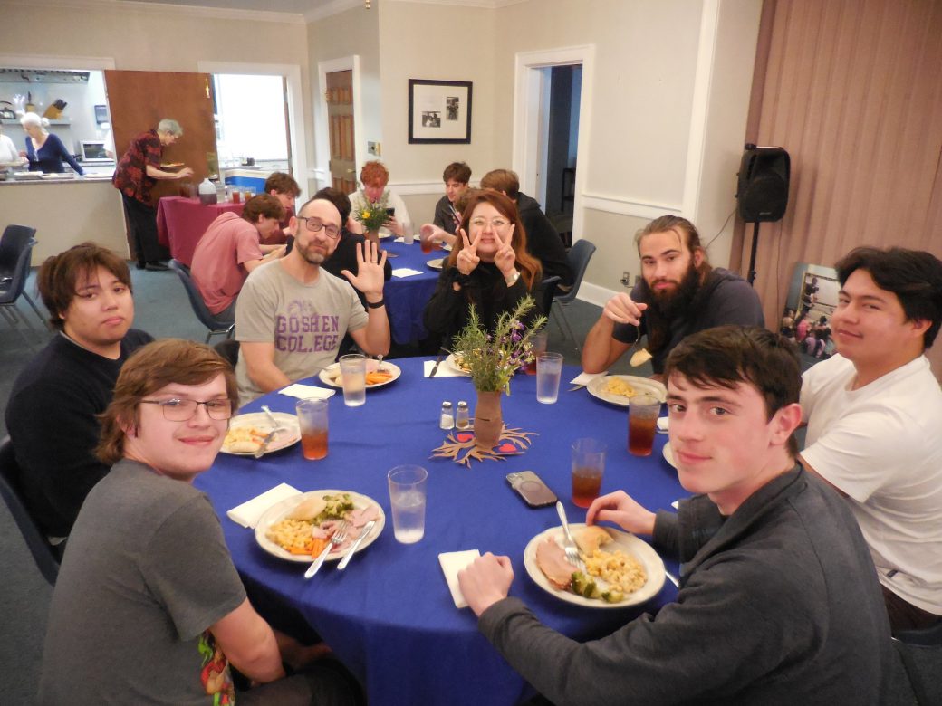 People eating pasta with chicken and brocoli