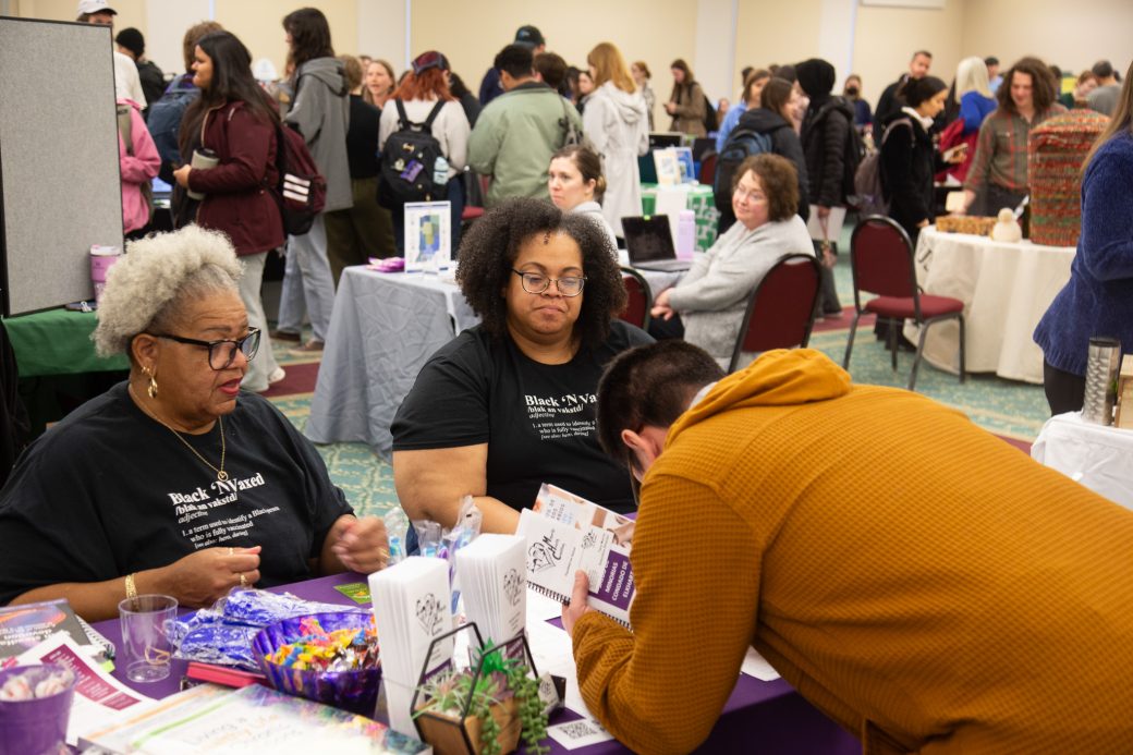 Two womten and a man talking a Community Engagement Fair