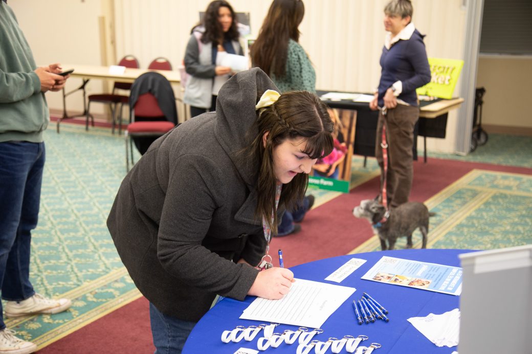 A woman writing in a paper at Community Engagement Fair