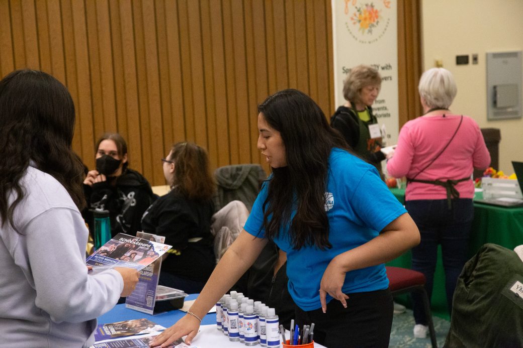 An employee of the Community Engagement Fair talking to a woman