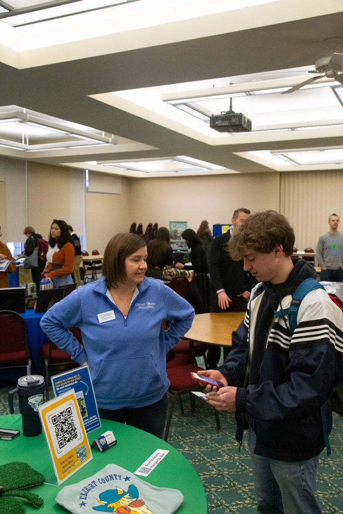 A employee of the Community Engagement Fair talking with a man