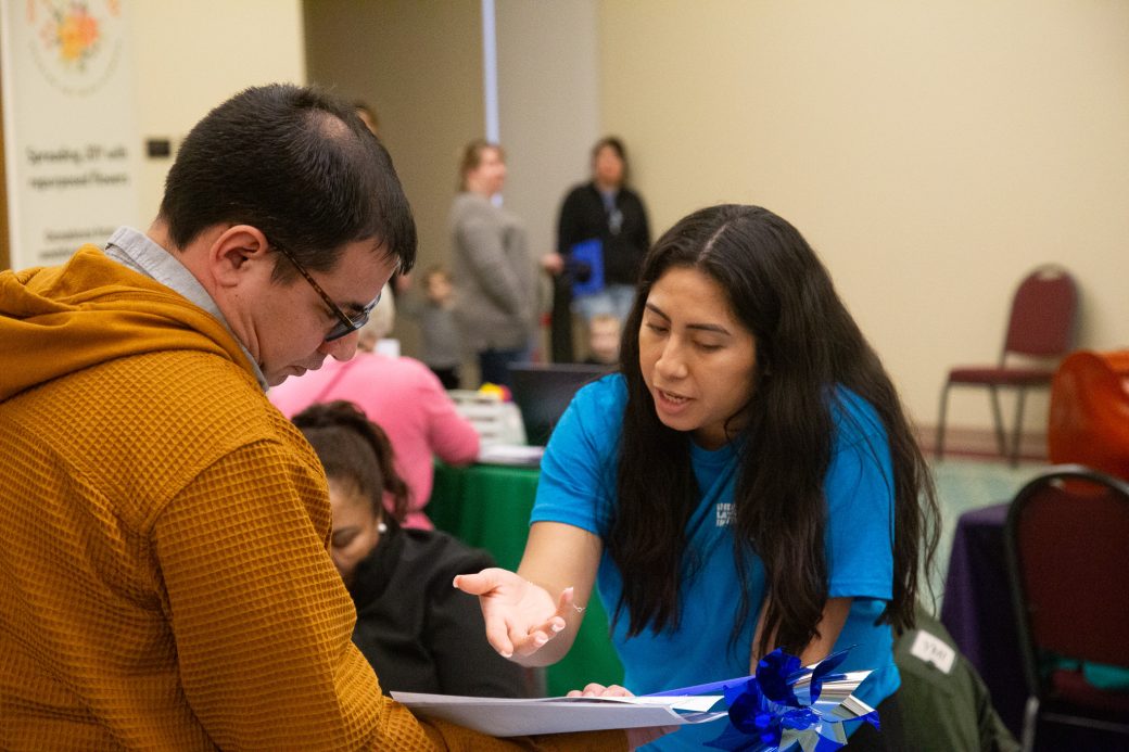 An employee of the Community Engagement Fair talking to a man