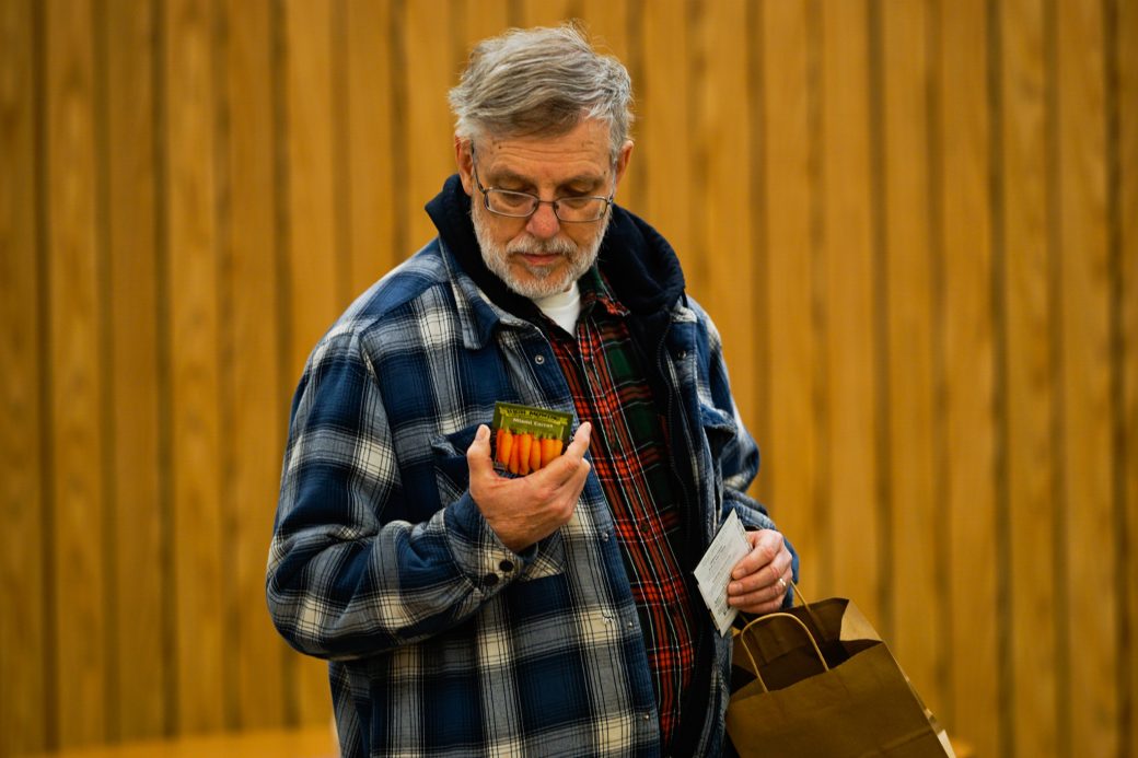 Man with a bag looking in a seed pack