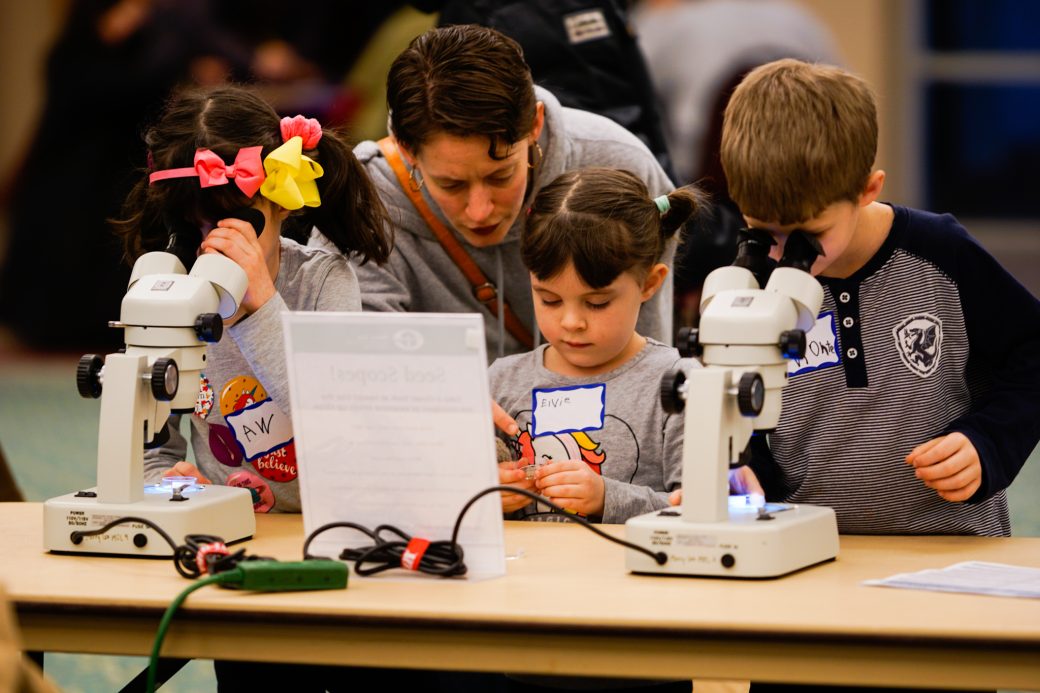 Kid looking in a microscope at Michiana Regional Seed Swap