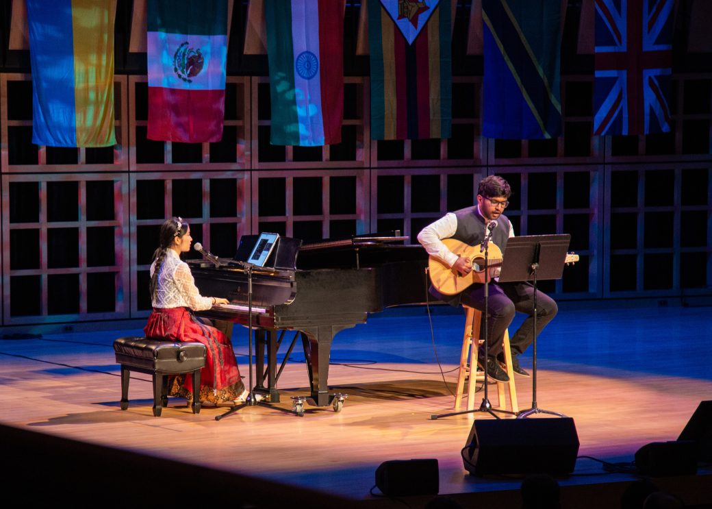A man playing piano and a man playing an acoustic guitar