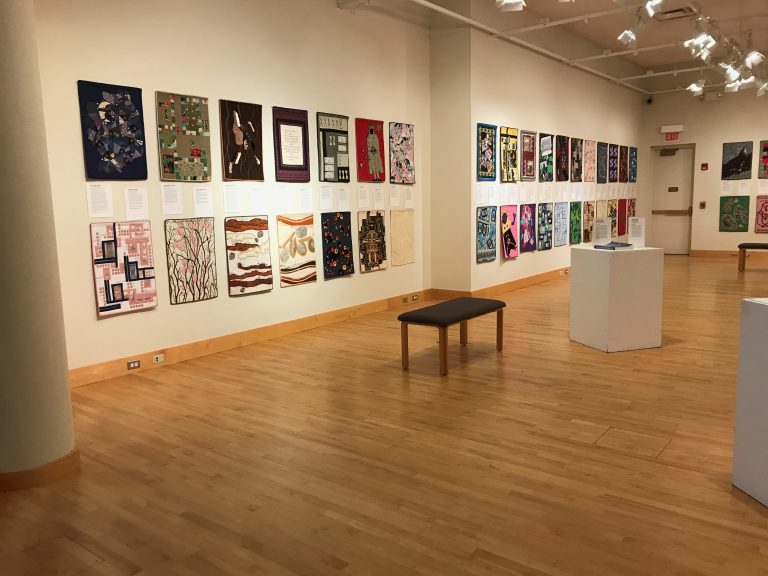 A photo of a quilt exhibit on the wall of a gallery