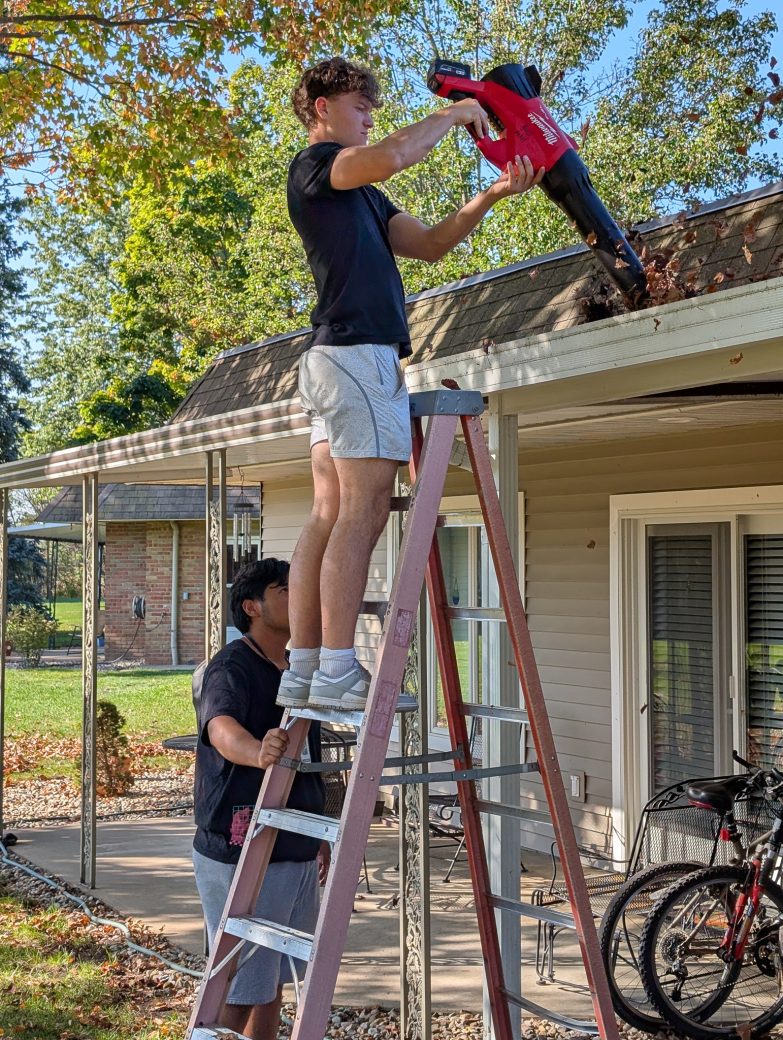 A boy using a leaf blower in the roof of a house