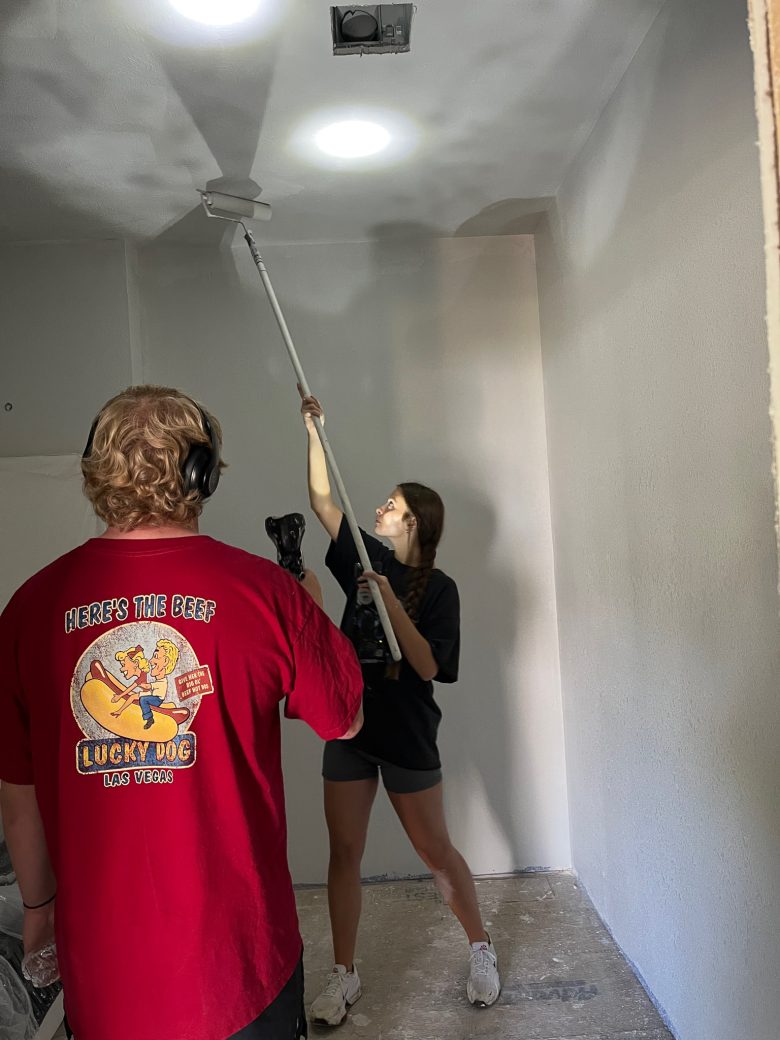 A man with a light helping a woman to painting the roof