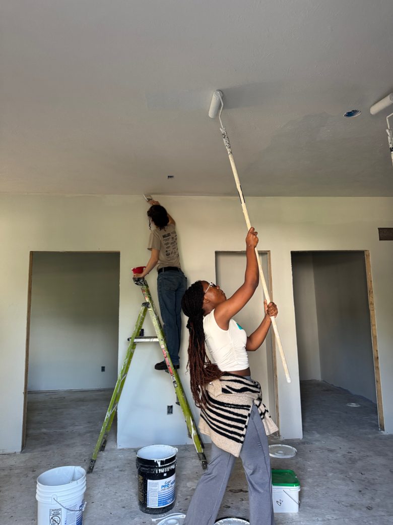 Two women painting a roof