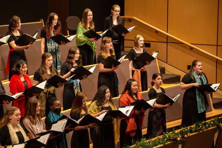 A women's choir sings together, holding folders