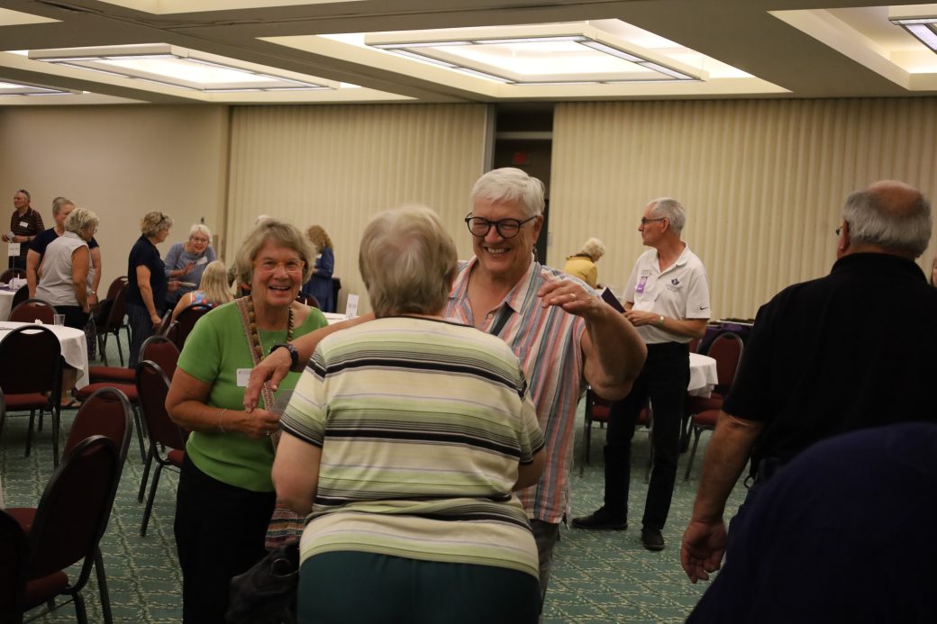 Smiling older nursing alumna chat in small group