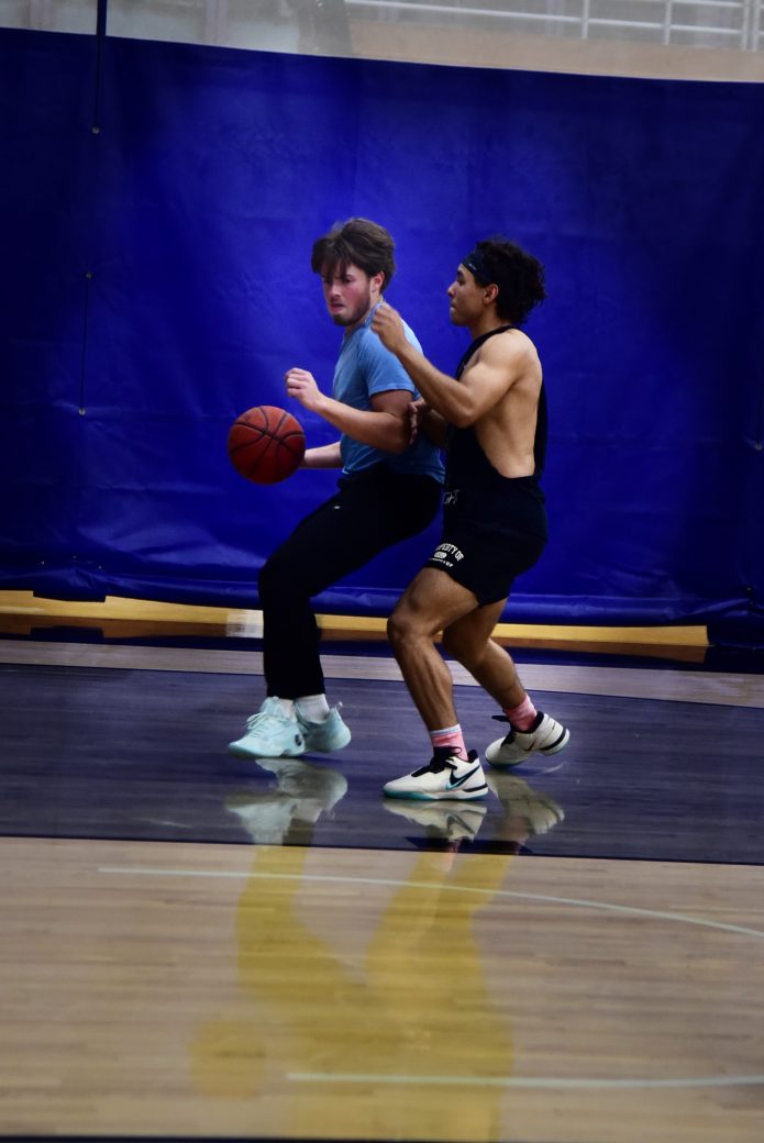 Player in black tanktop gaurds player in blue shirt with the basketball