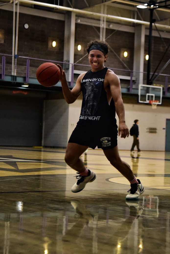 Male player in black tank running on on court