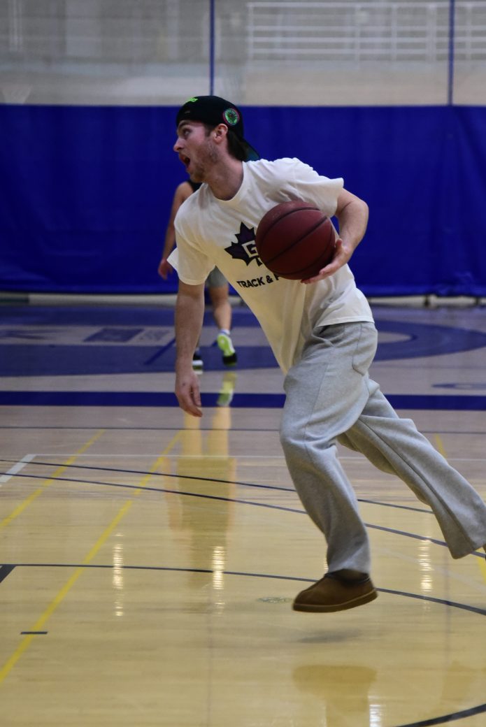 Student in white shirt dribbling basketball down the court