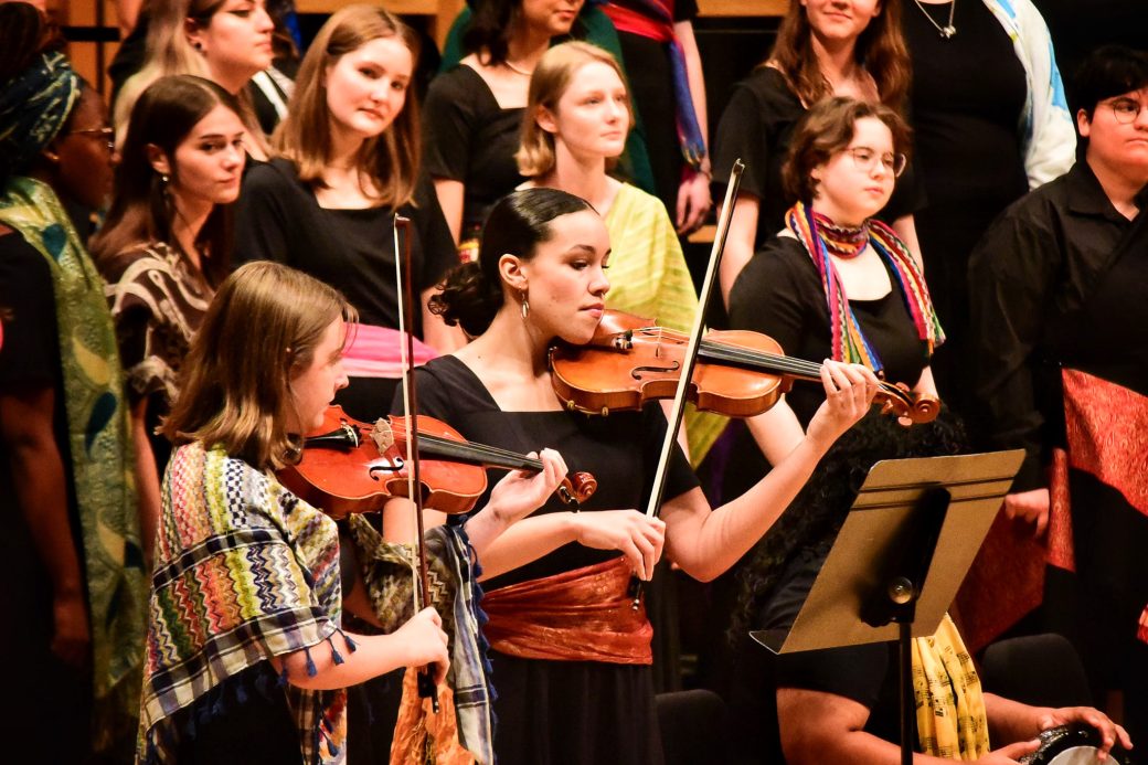 Students playing string instruments on stage