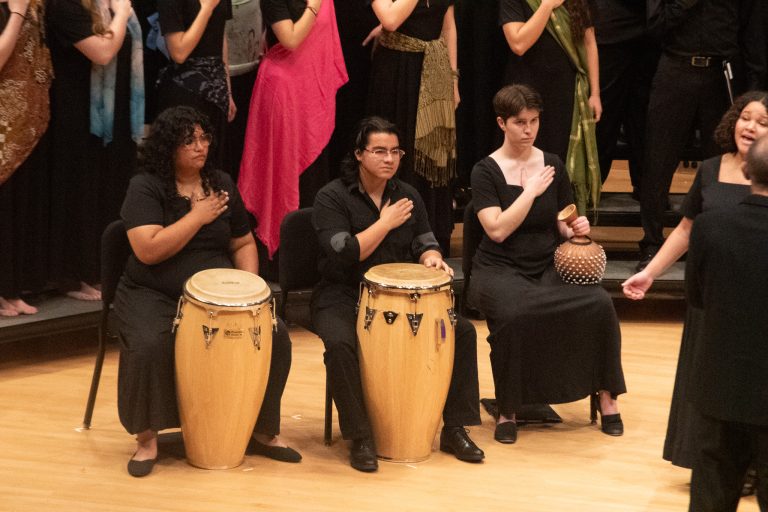 Student performers playing large hand drums