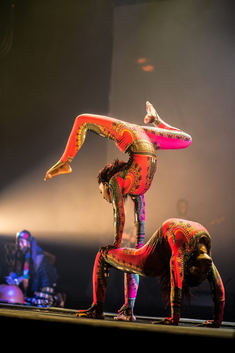 An artist performs a handstand on top of another artist.
