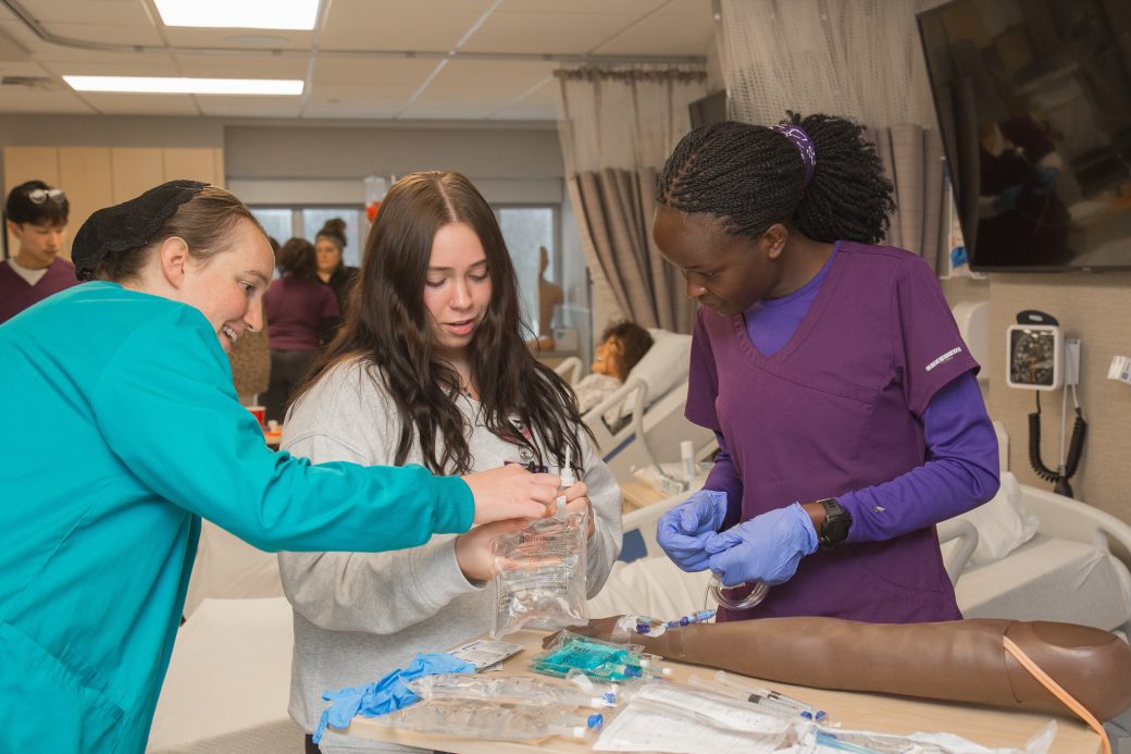 Students working as a group to insert an IV into a manikin arm