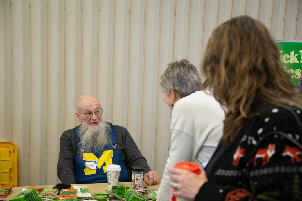 man sitting at a booth talking to people