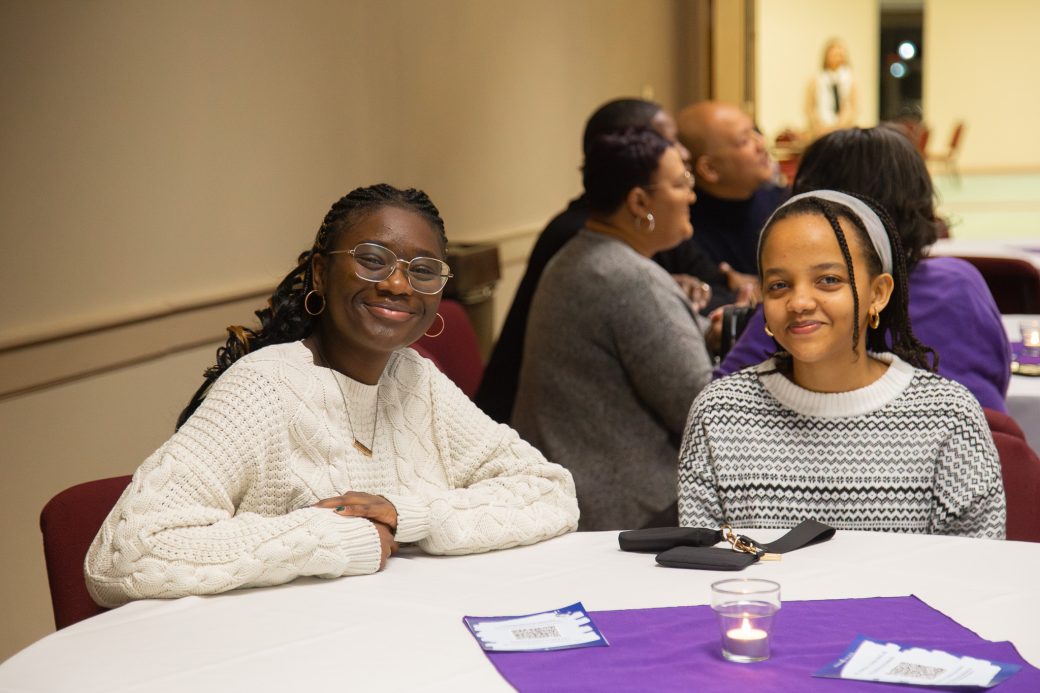Students smiling and sitting at a table
