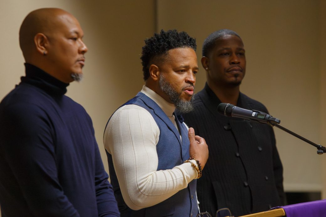 Three men speaking into a mic