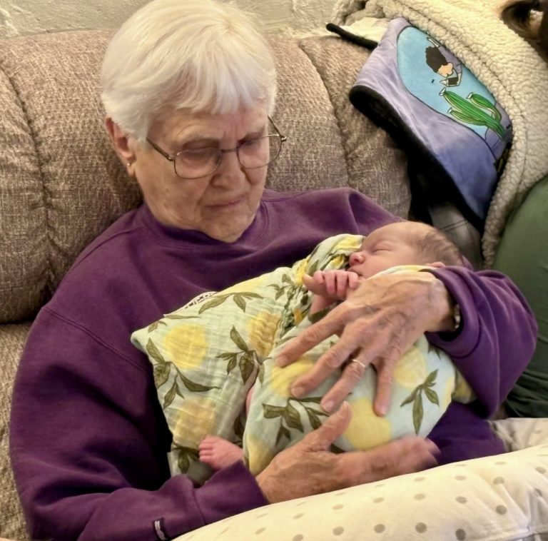 older woman holding newborn baby in a blanket