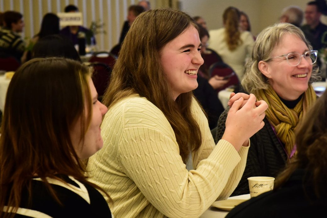 People at a table smiling at Celebrate Scholars Day