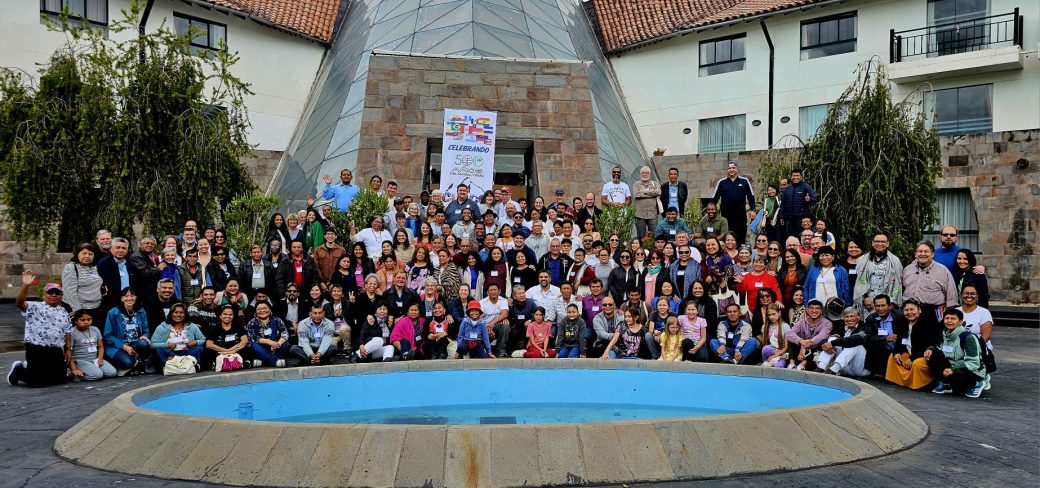 Group of more than one hundred people standing in front of a building.